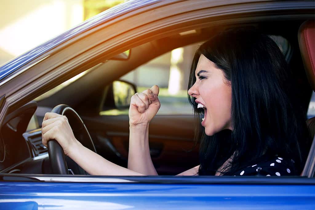 Lady screams and shakes fist while driving a car