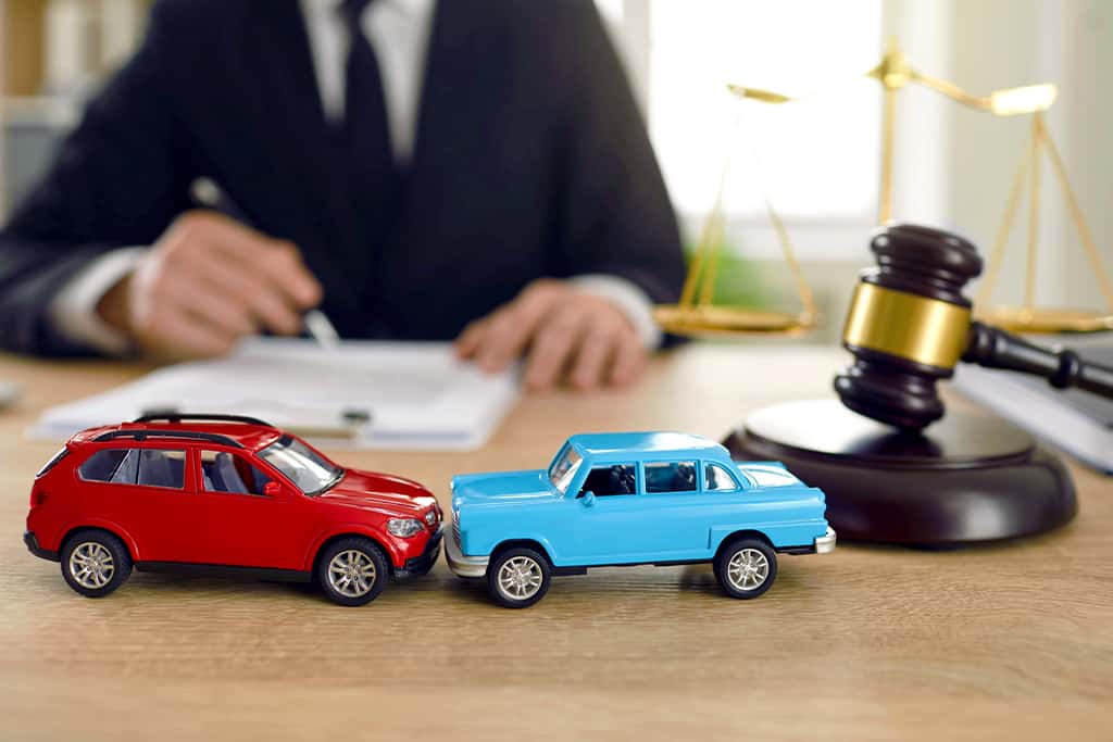 2 miniature cars on a table by a judge's gavel
