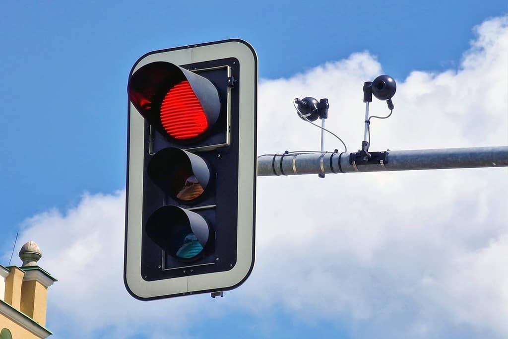 A traffic light with two traffic cameras next to it