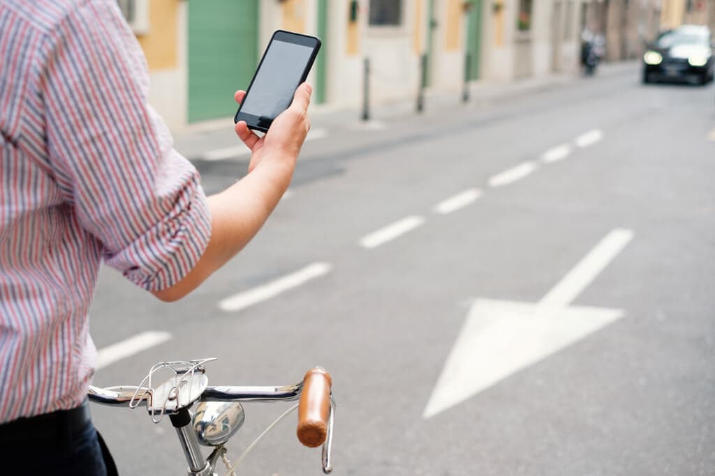 Cyclist standing in the road distracted by their cell phone.