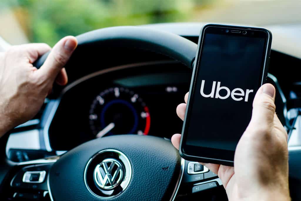 Uber driver holding smartphone in Volkswagen car.