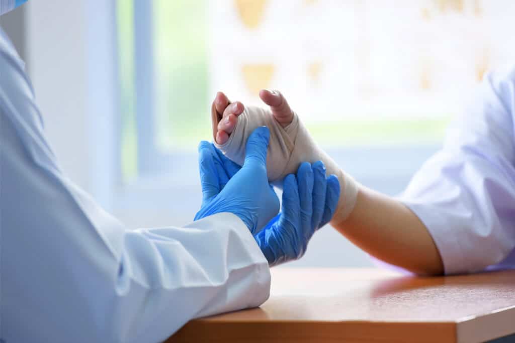 A doctor holding a patient's wrist wrapped in a bandage.