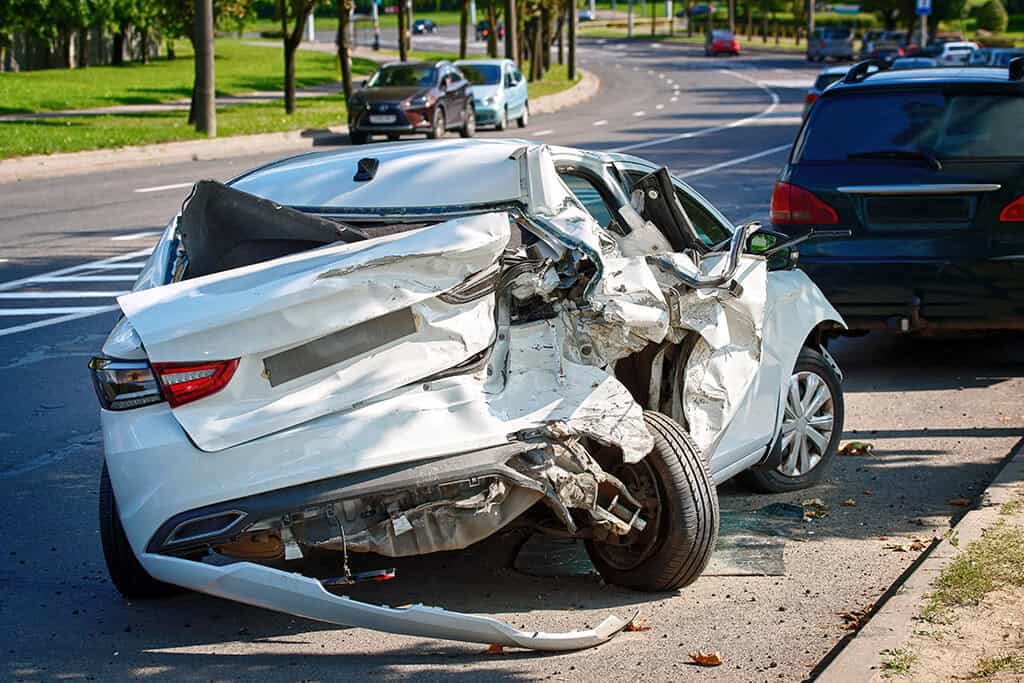 Severely wrecked white vehicle, totaled frame after rear-end collision