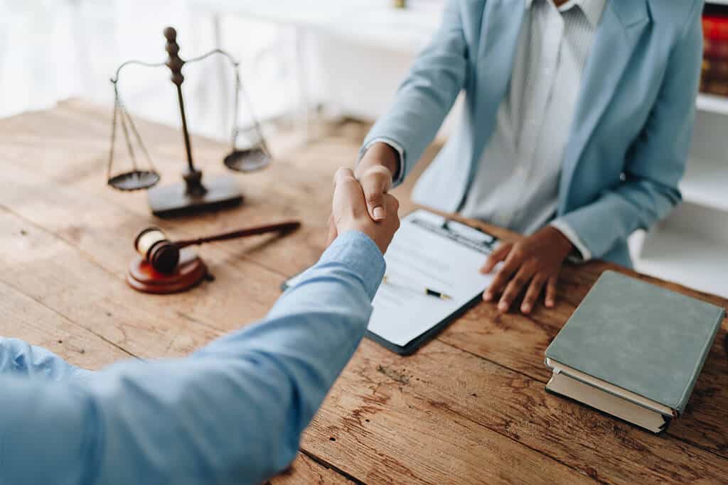 An attorney shakes hands to agree on a contract with a client